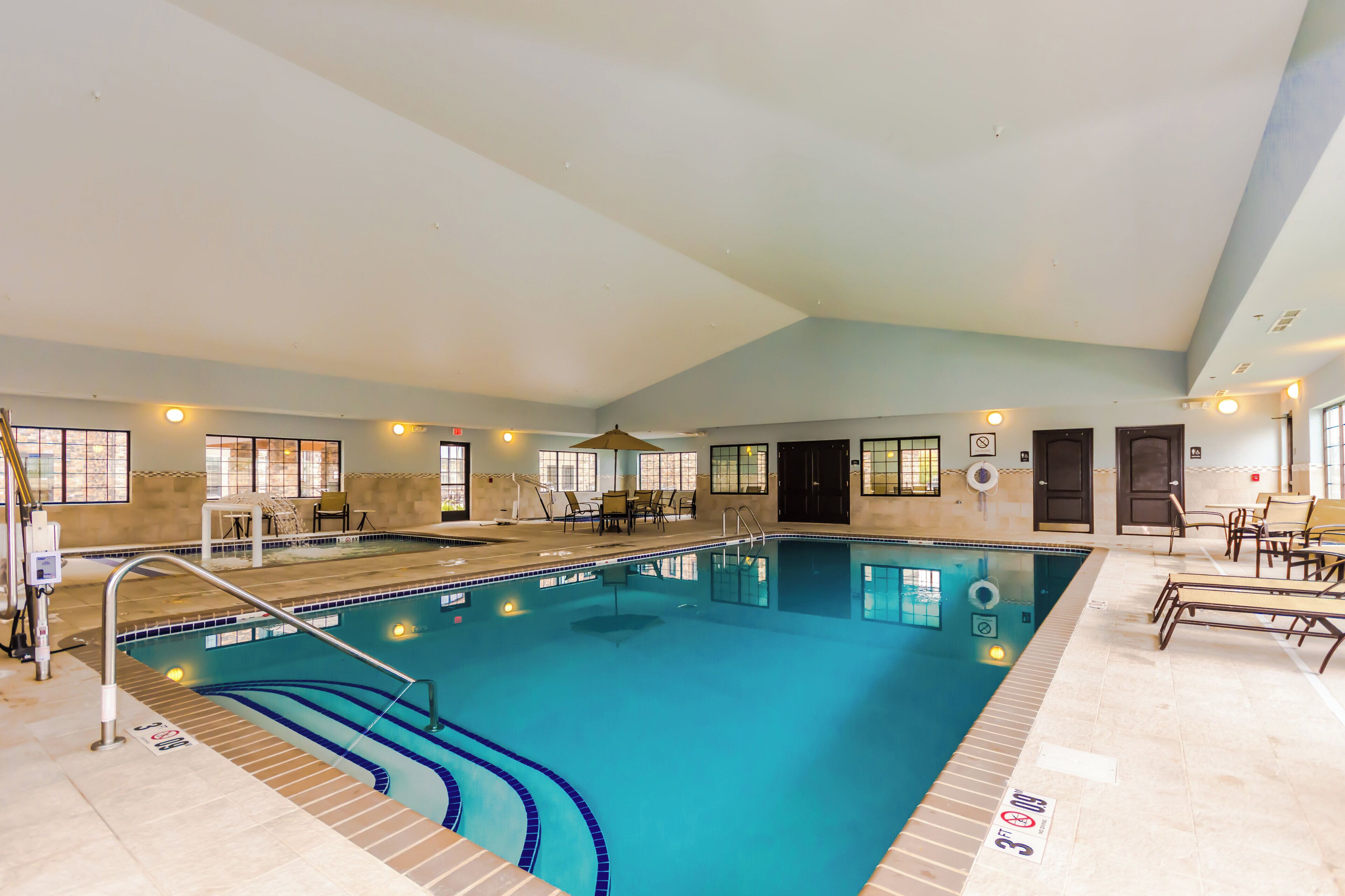 An indoor swimming pool with clear lanes, a lifeguard chair, and a sunshade.