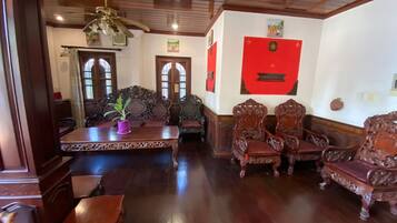 A traditional room with wooden furniture, a ceiling fan, and a red wall decoration.