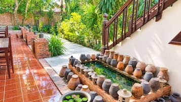 A courtyard with a tiled floor, a brick wall, a wooden staircase, and a variety of pottery.