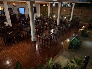 A restaurant with multiple tables and chairs, a tiled floor, and hanging lights. - Vangsavath Hotel (Luang Prabang)