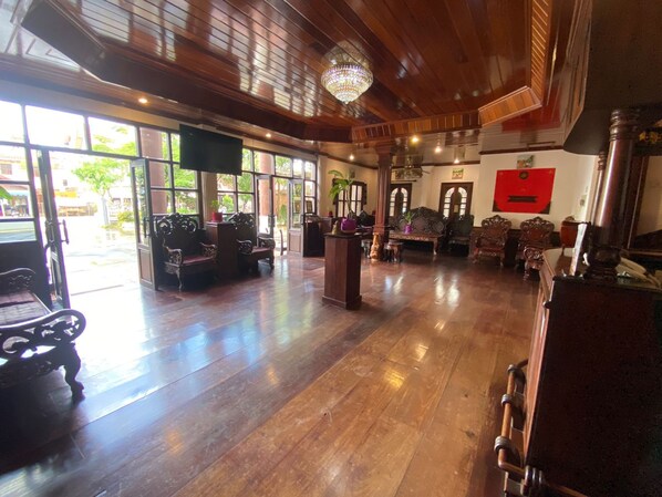 A spacious lobby with wooden flooring, ornate furniture, and large windows allowing natural light. - Vangsavath Hotel (Luang Prabang)