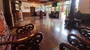 A spacious lobby with wooden flooring, ornate furniture, and large windows allowing natural light. - Vangsavath Hotel (Luang Prabang)