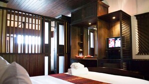 A hotel room with a bed, a television, a desk with a chair, and a wooden partition. - Vangsavath Hotel (Luang Prabang)