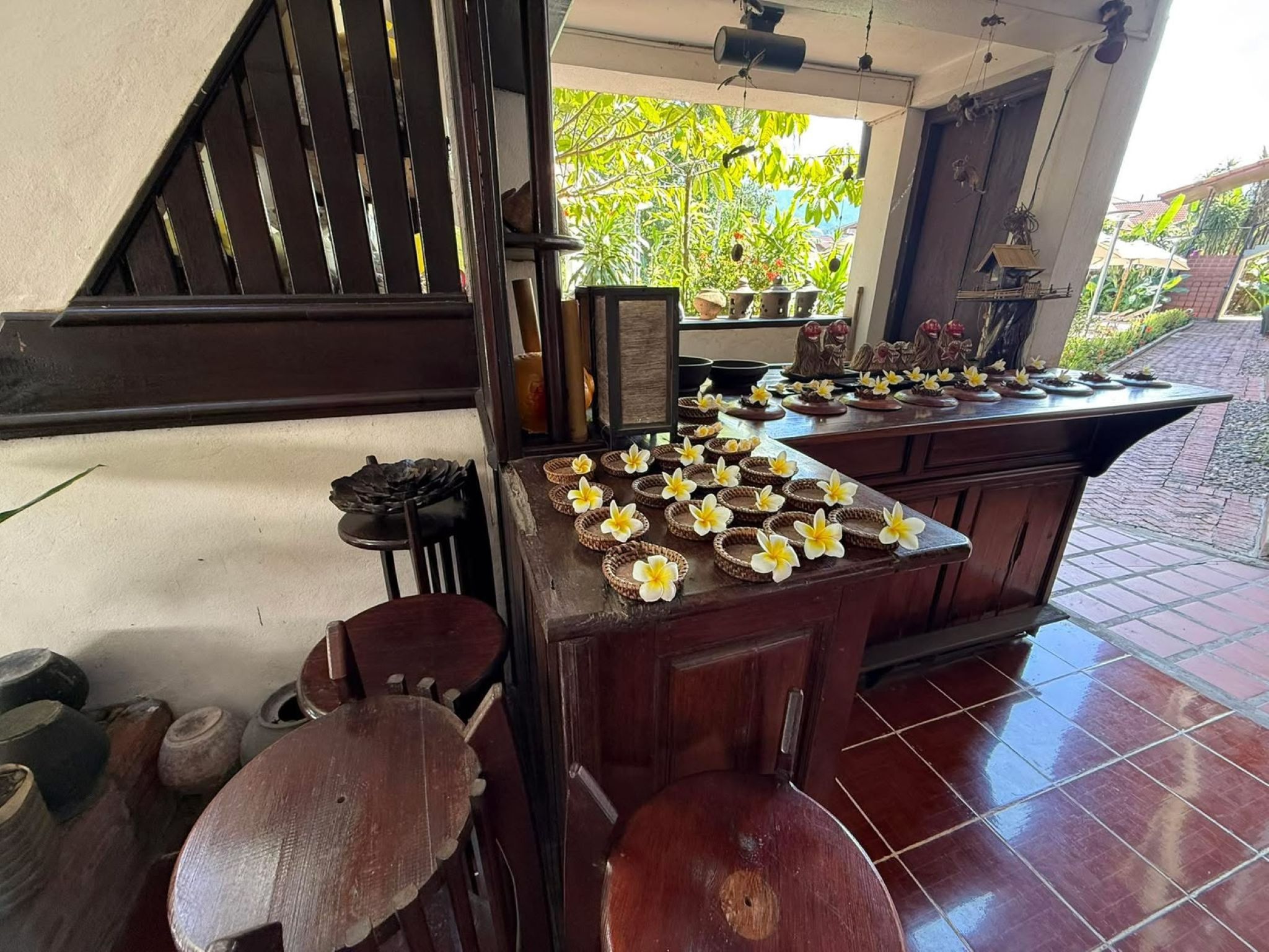 Zona de bar con barra de madera, piso de baldosas, una escalera y vista a zonas verdes.