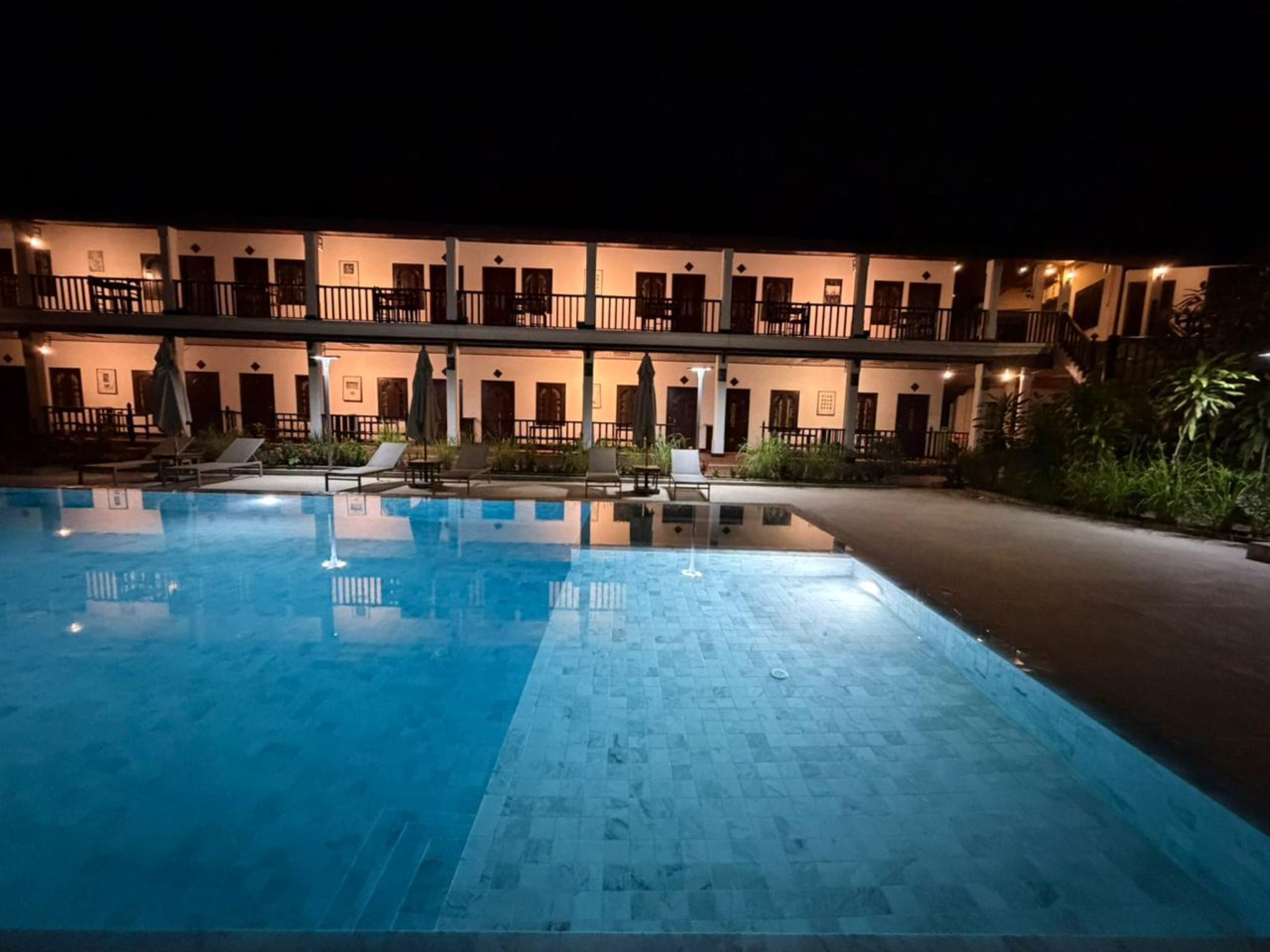Un hotel con piscina, varios balcones y mobiliario de exterior.