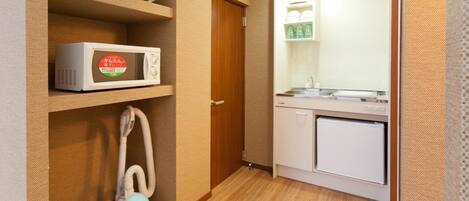 A compact kitchen with a microwave, a small refrigerator, and a sink.