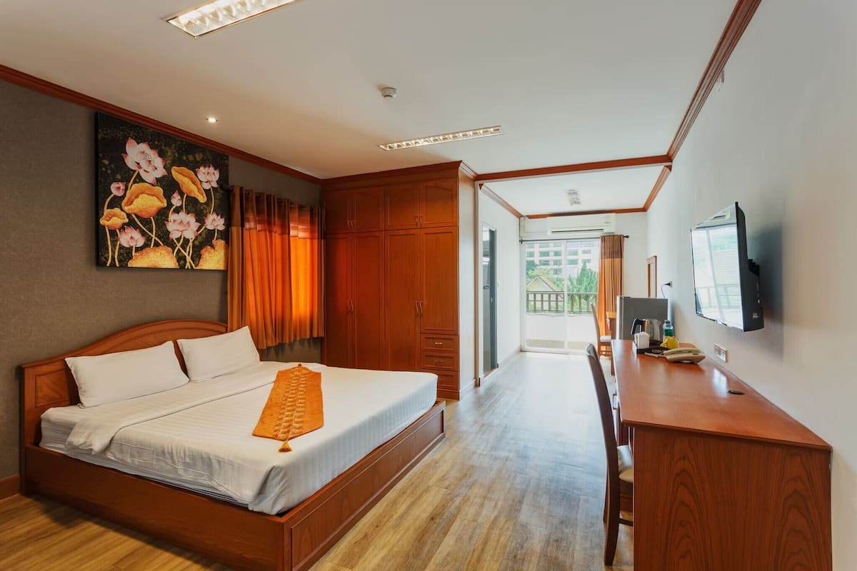 Quarto com cama de madeira, escrivaninha, televisão e um quadro na parede.