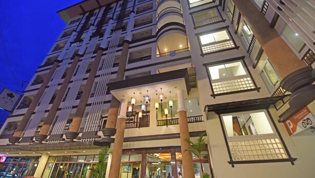 A multi-story hotel with a central atrium, balconies, and a ground-level entrance. - V Residence Chiangmai Hotel (Chiang Mai)