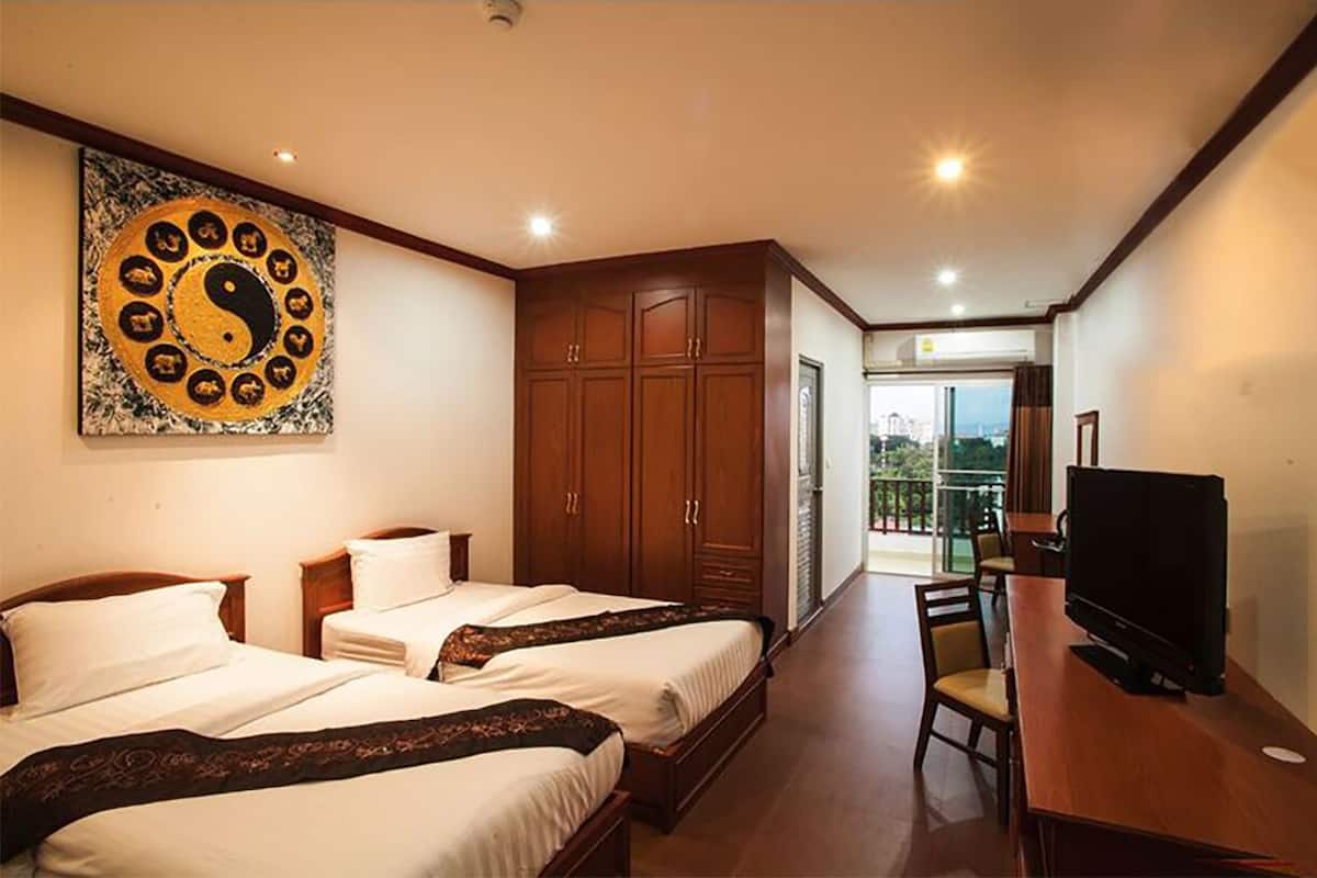 Quarto de hotel com duas camas, televisão, guarda-roupa de madeira e uma grande obra de arte na parede.