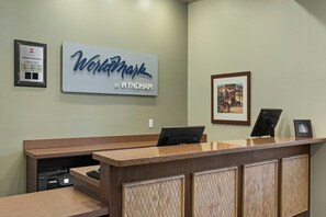 A reception desk with a framed sign reading 'WorldMark by Wyndham,' a framed award, and a framed picture on the wall.
