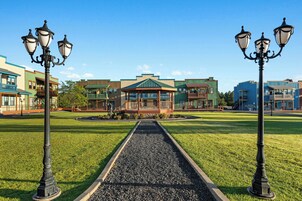 A building with a central pavilion, surrounded by a well-maintained lawn and street lamps.
