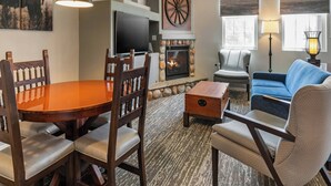 A living room with a fireplace, a television, a dining table with chairs, a sofa, and a lamp. - WorldMark Bison Ranch (Overgaard)