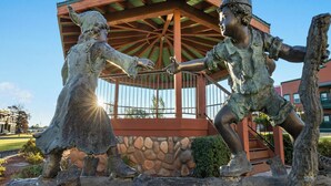 A statue of two figures in a gazebo with a stone wall and wooden beams. - WorldMark Bison Ranch (Overgaard)