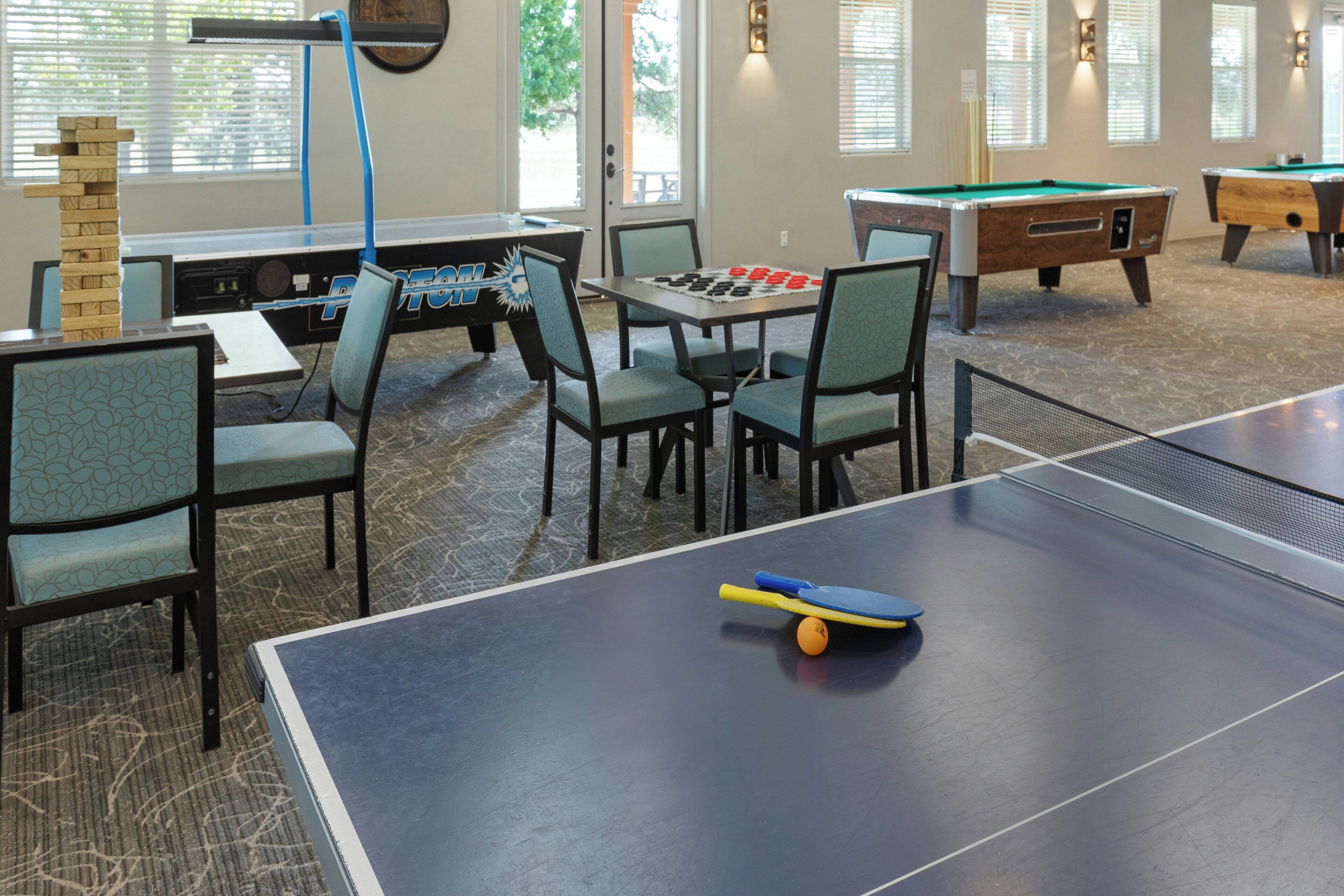 A billiards room with tables, chairs, and a ping pong table.