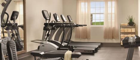 Un gimnasio con cintas de correr, elípticas y pesas libres.