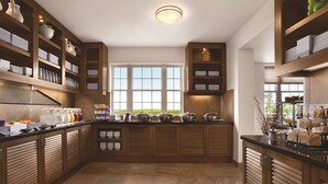A modern kitchen with wooden cabinets, a large window, and a countertop with various food items. - HYATT house Minot (Minot)