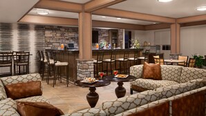 A spacious indoor area with a bar, seating arrangements, and a kitchen in the background. - HYATT house Minot (Minot)