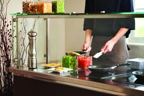 Una encimera de cocina con diversos alimentos y una persona cocinando.