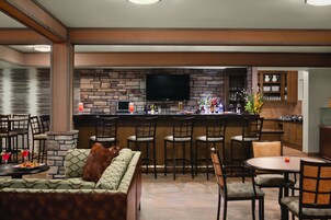 Una cocina moderna con protector de piedra, un televisor de pantalla plana y una zona de bar con taburetes.