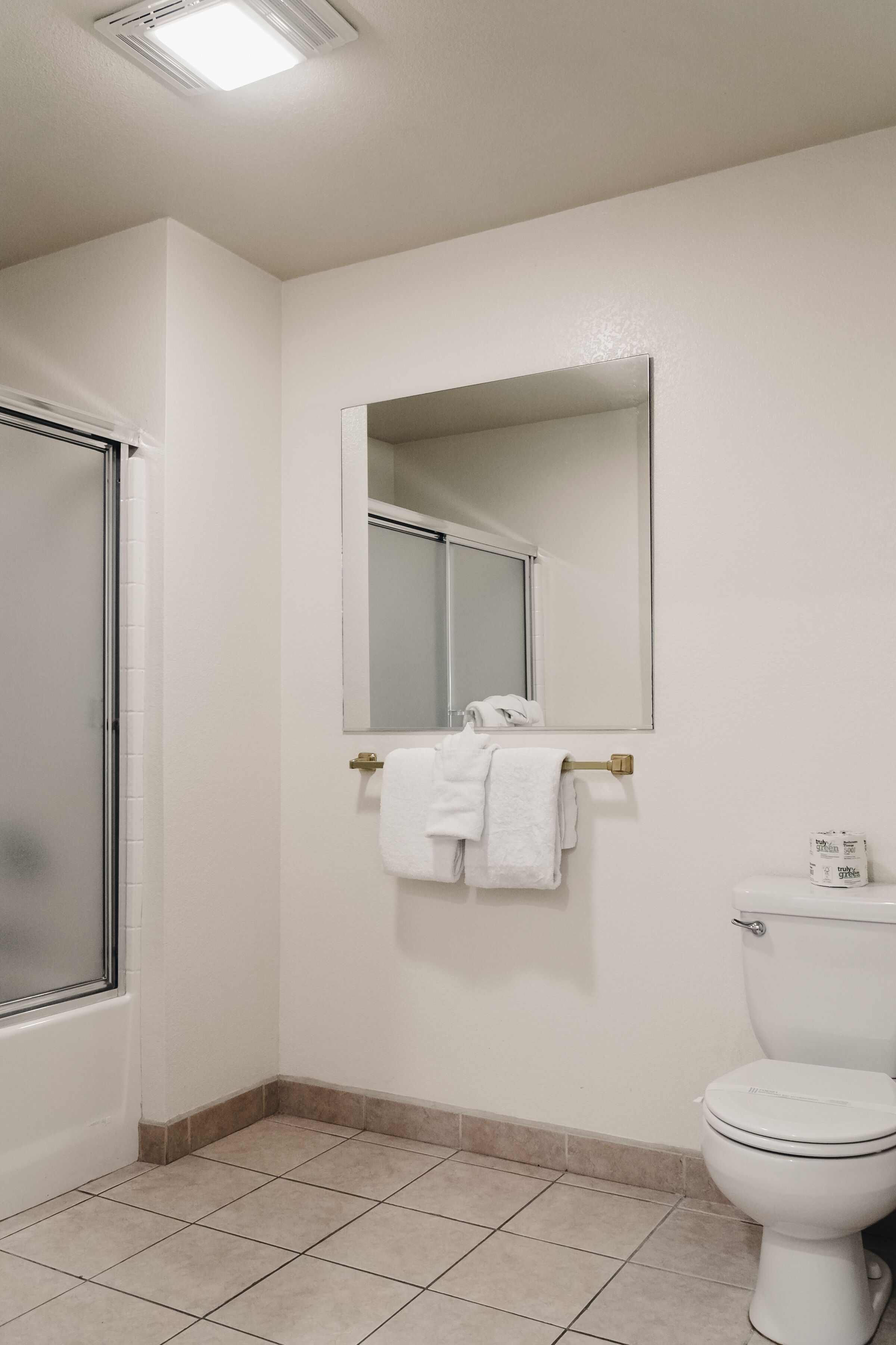 Un baño con inodoro, espejo y toallero.