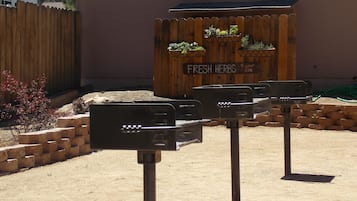 A garden area with a wooden fence, a sign reading "FRESH HERBS", and a brick planter with plants.