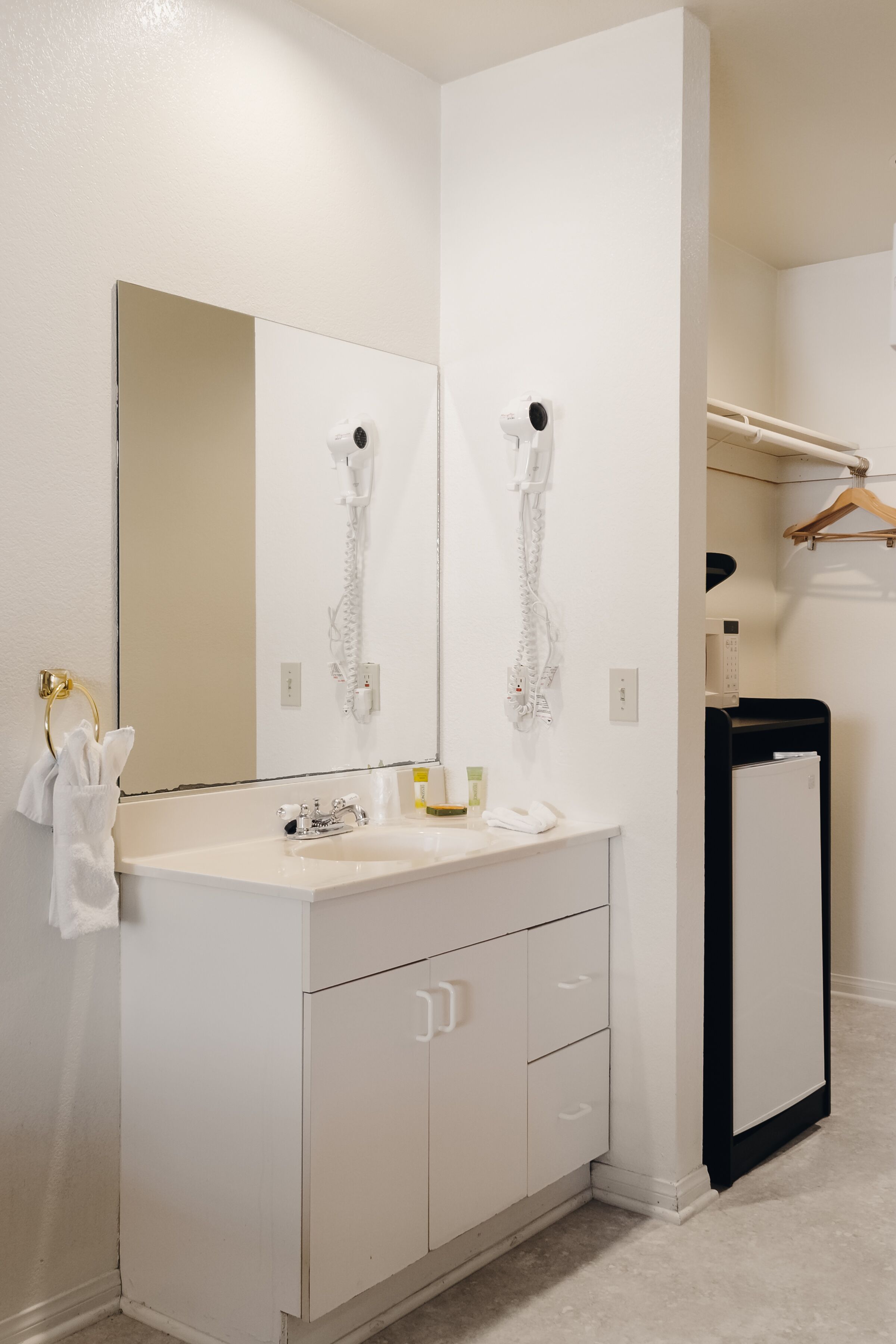 Une salle de bain moderne avec un meuble-lavabo blanc, un grand miroir et un sèche-cheveux fixé au mur.
