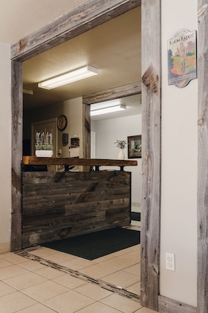 Una zona de recepción con un mostrador de madera, un reloj en la pared y un cartel de bienvenida.