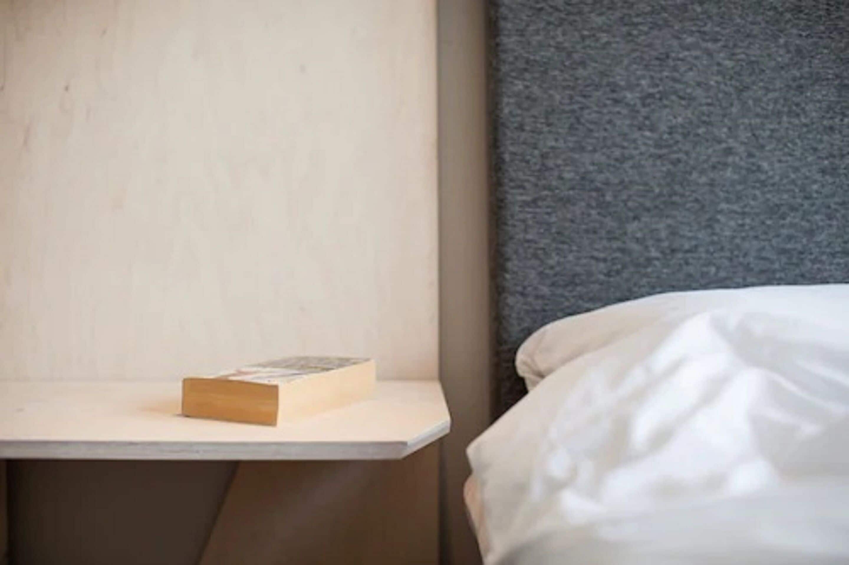 Un dormitorio con una cama, una mesita de noche y un libro.