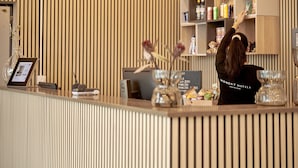 A reception desk with a wooden slat wall, a digital display, and a shelf with various items.