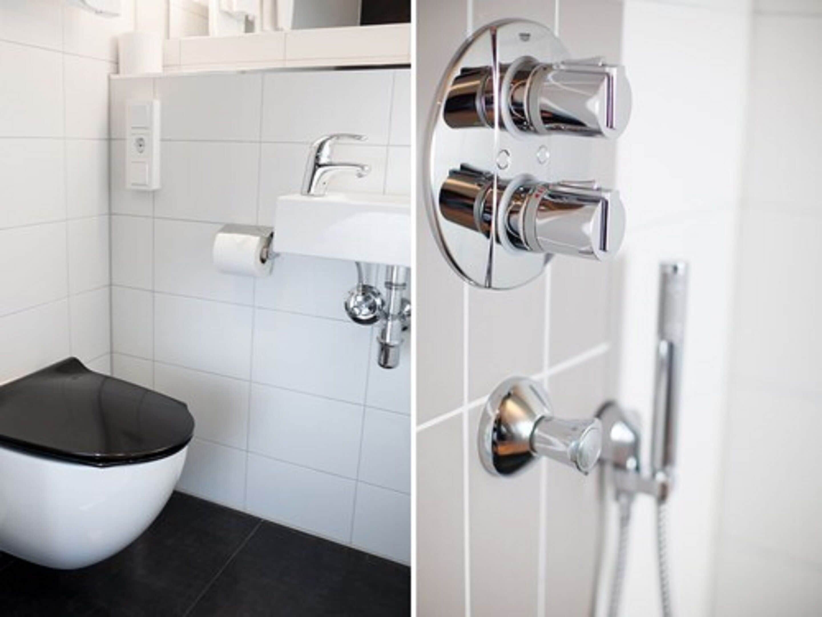 A modern bathroom with a white toilet, a chrome sink, and a shower with a chrome faucet.