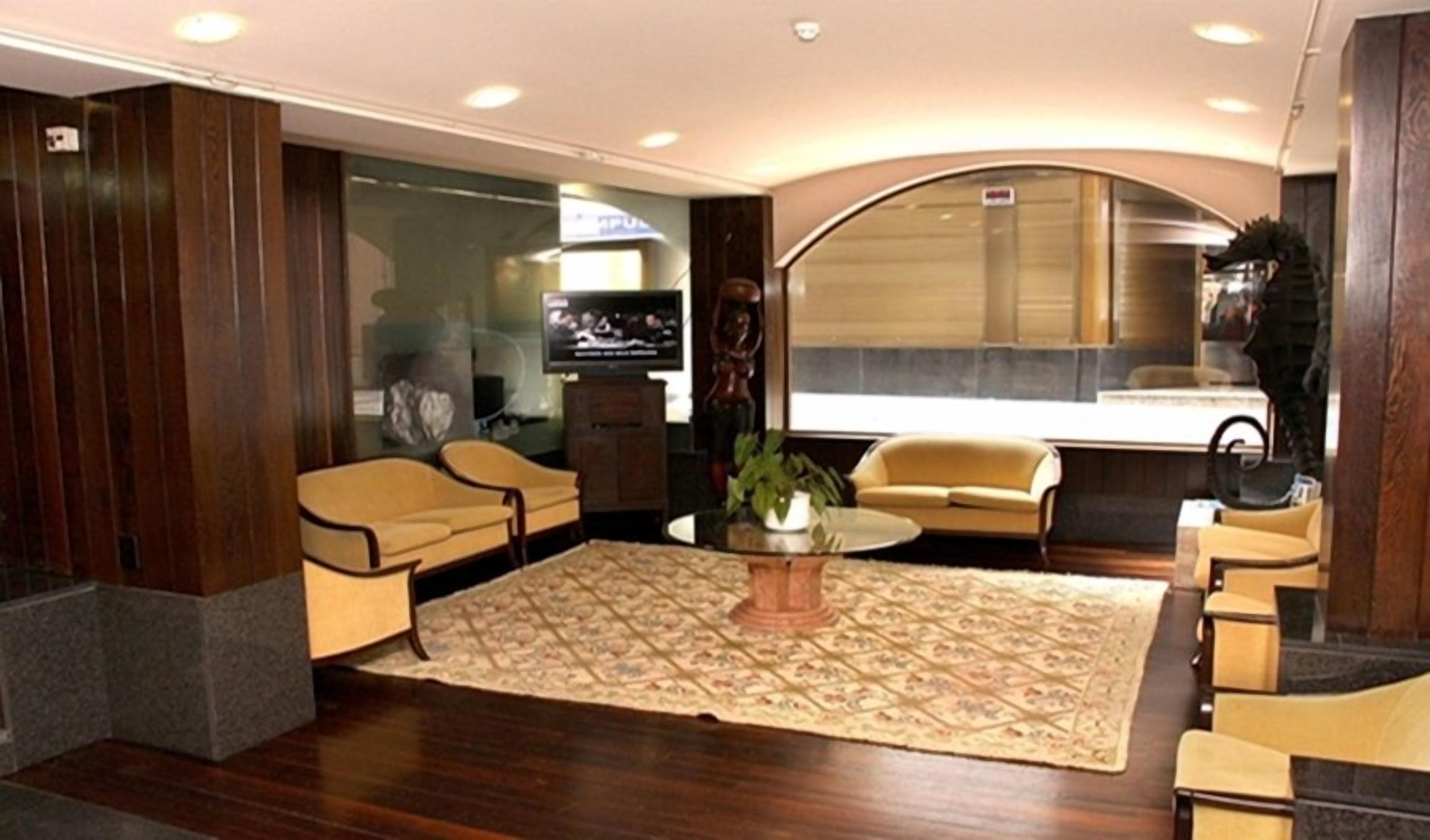 Un vestíbulo moderno con un tapete grande de diseño, varios sofás y un televisor.