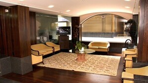 A modern hotel lobby with a central seating area, a television, and a decorative seahorse statue.