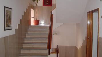 A staircase with a wooden handrail, a potted plant, and a framed picture on the wall.