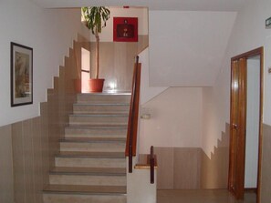 A staircase with a wooden handrail, a potted plant, and a framed picture on the wall. - Luso Brasileiro (Povoa De Varzim)