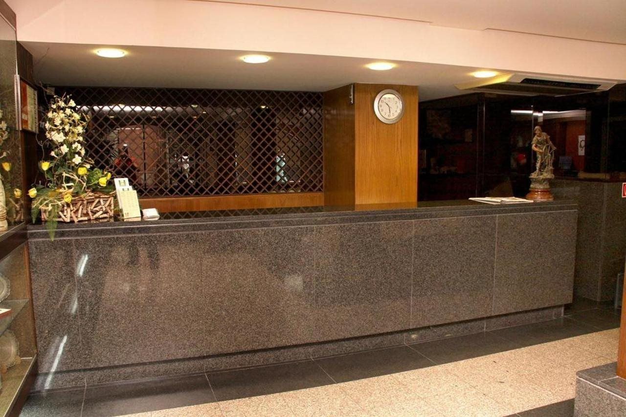 A reception desk with a clock, a decorative plant, and a statue.