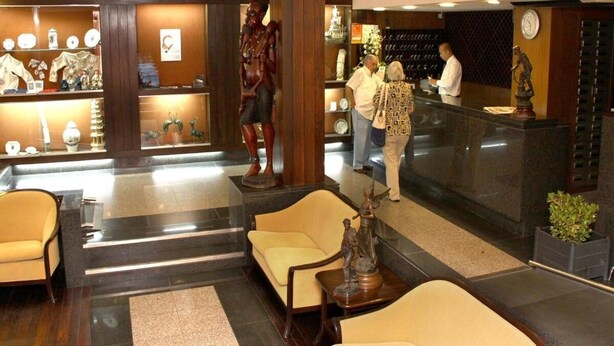 A lobby with a reception desk, seating area, and decorative statues. - Luso Brasileiro (Povoa De Varzim)