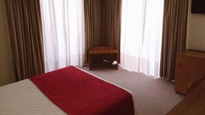A hotel room with a bed, a wooden bench, and a TV on the wall. - Luso Brasileiro (Povoa De Varzim)