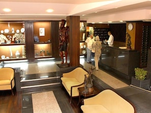 Un vestíbulo con mostrador de recepción, zona de estar y elementos decorativos.