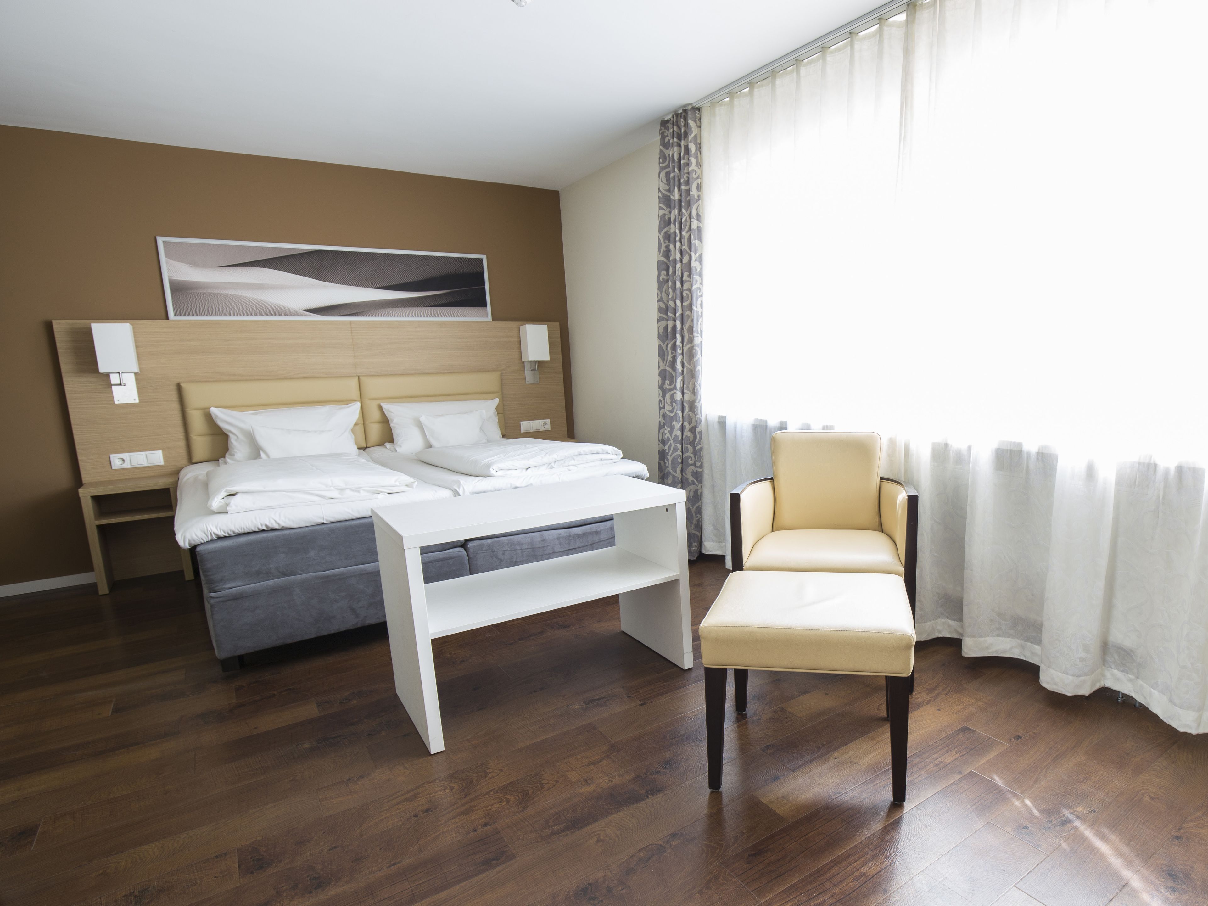 Habitació d'hotel amb un llit, taules de nit, una cadira i vistes a l'exterior.