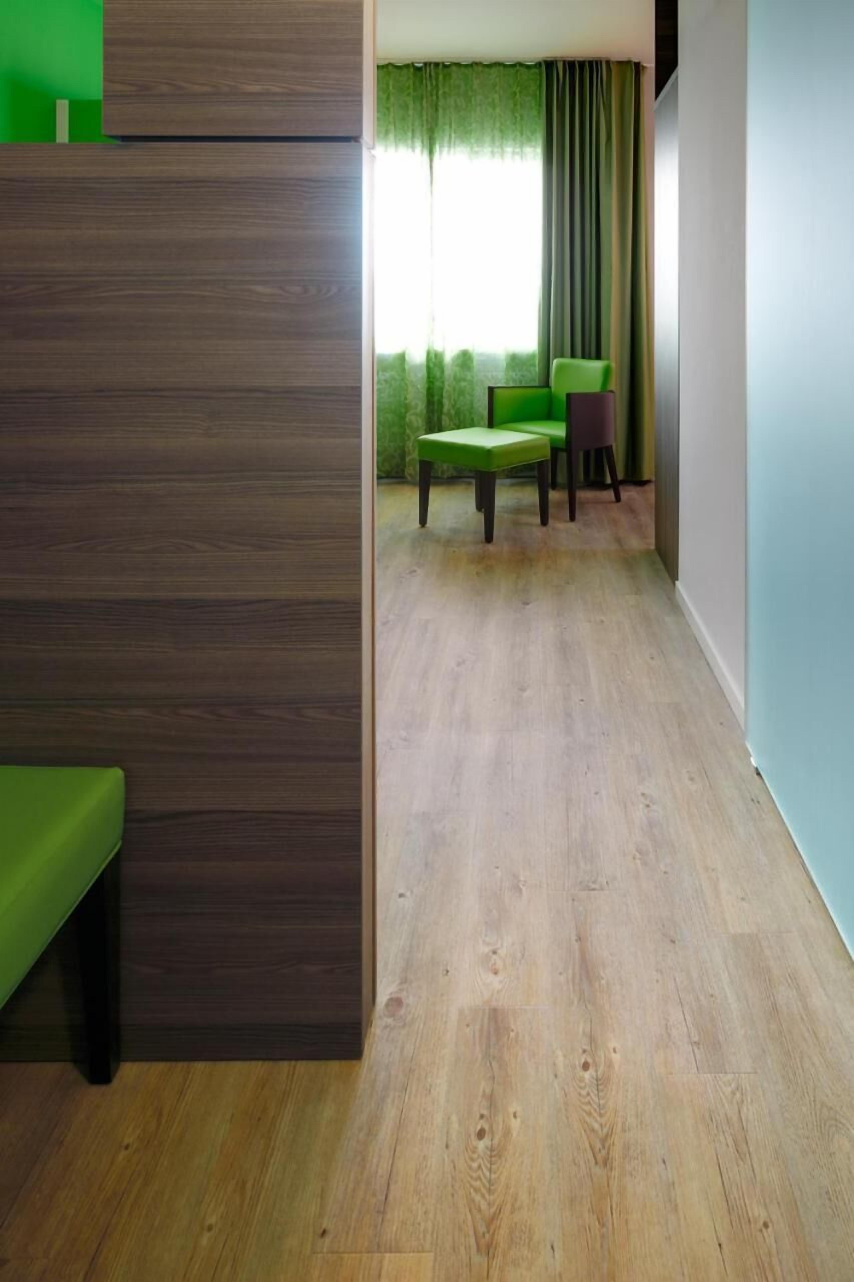 Ein Zimmer mit Holzboden, einem grünen Sofa und einem grünen Sessel.