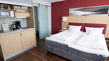 Ein Hotelzimmer mit Bett, einer Küchenzeile und einer roten Akzentwand.