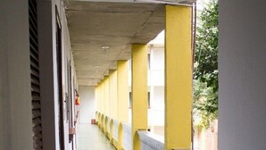 Un corridoio con pilastri gialli, ringhiere bianche e pavimento piastrellato.