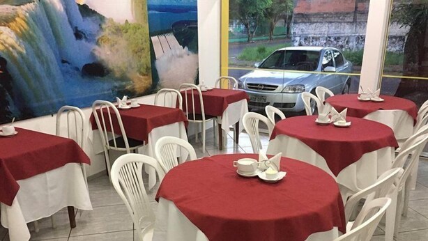 Un ristorante con tavoli rotondi ricoperti da tovaglie rosse e sedie bianche.