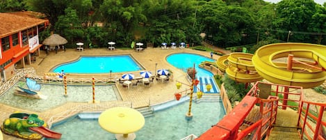 Un área de piscina con varias piscinas, toboganes acuáticos y tumbonas.