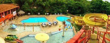 Un área de piscina con varias piscinas, toboganes acuáticos y tumbonas.