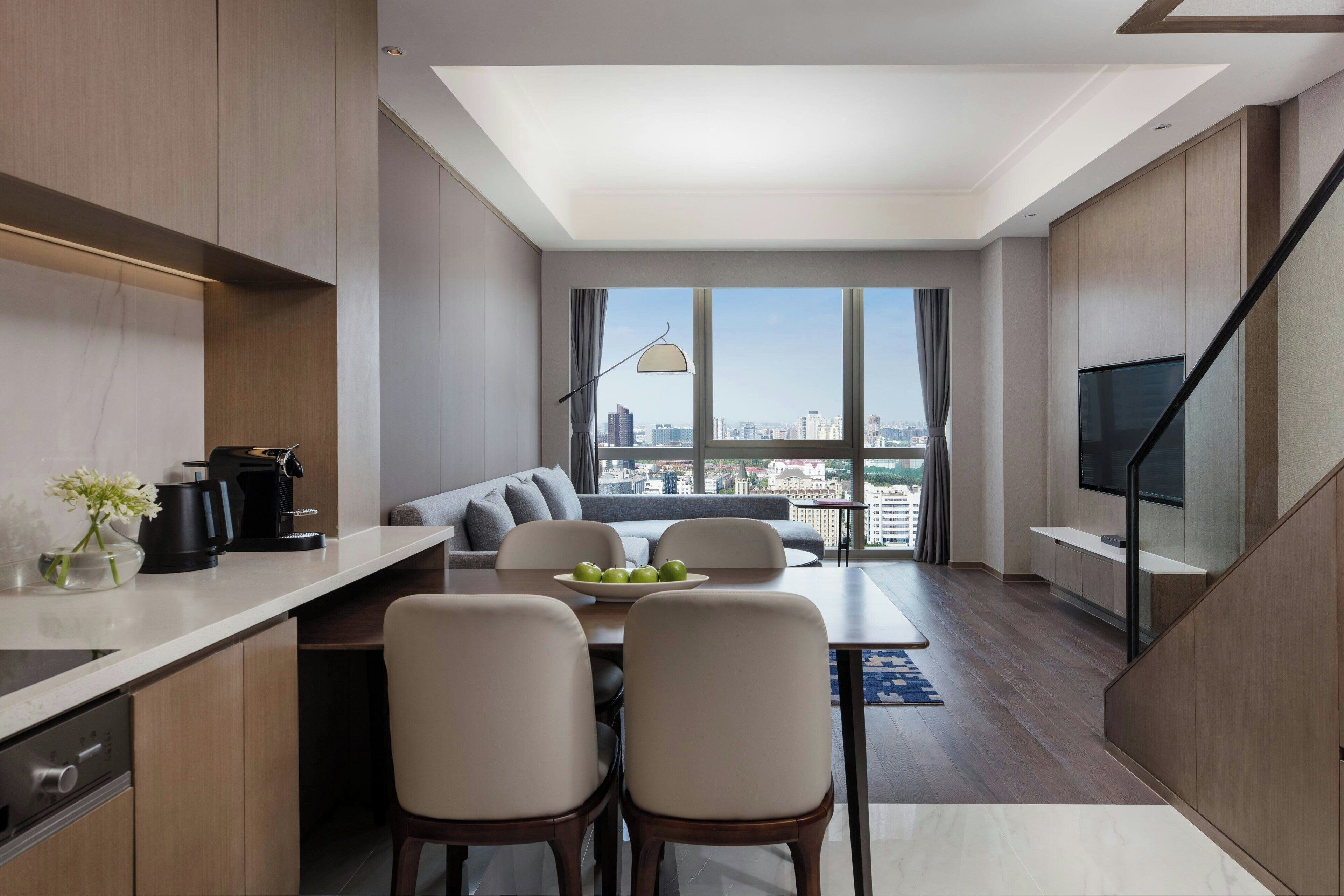 A modern kitchen with a dining area, a sofa, and a TV.