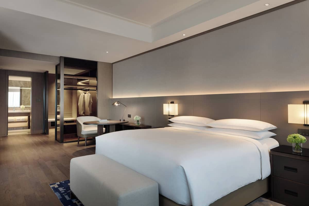 Een moderne hotelkamer met een groot bed, een bureau en een inloopkast.