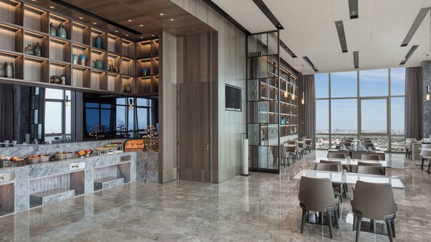 Ein modernes Restaurant mit Barbereich, Marmorarbeitsplatten und Blick auf die Stadt.