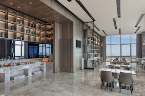 A modern restaurant with a bar area, marble countertops, and a view of the city. - Shanghai Marriott Hotel Pudong East (Shanghai)