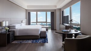 Ein modernes Hotelzimmer mit einem großen Bett, einem Schreibtisch, einem Sessel und einem Fernseher.